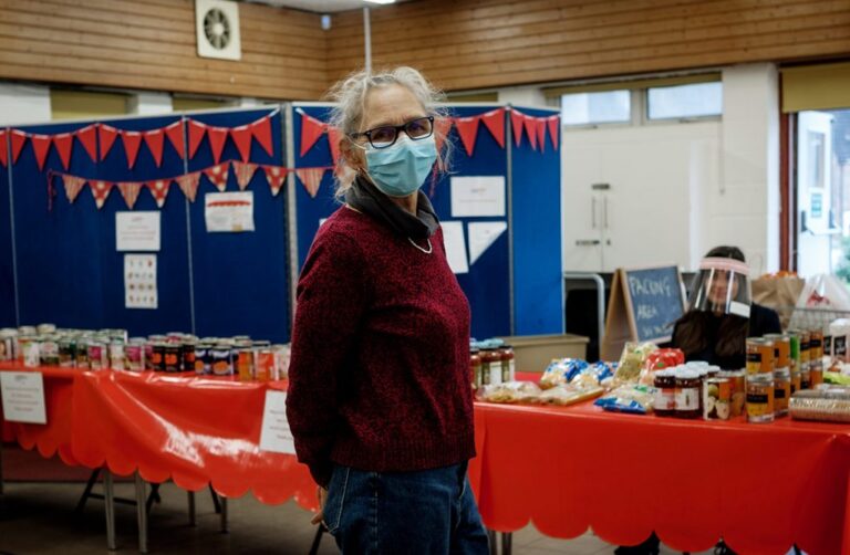 A volunteer infront of tables lined with tins of food