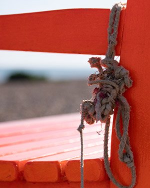 A close up photo of some rope hanging on a bench