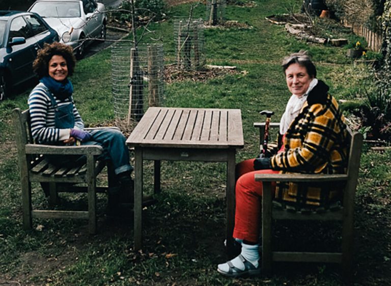 Two people sitting on a bench in a garden