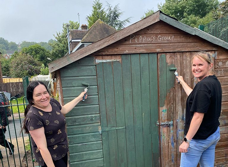 Two ladies painting a shed
